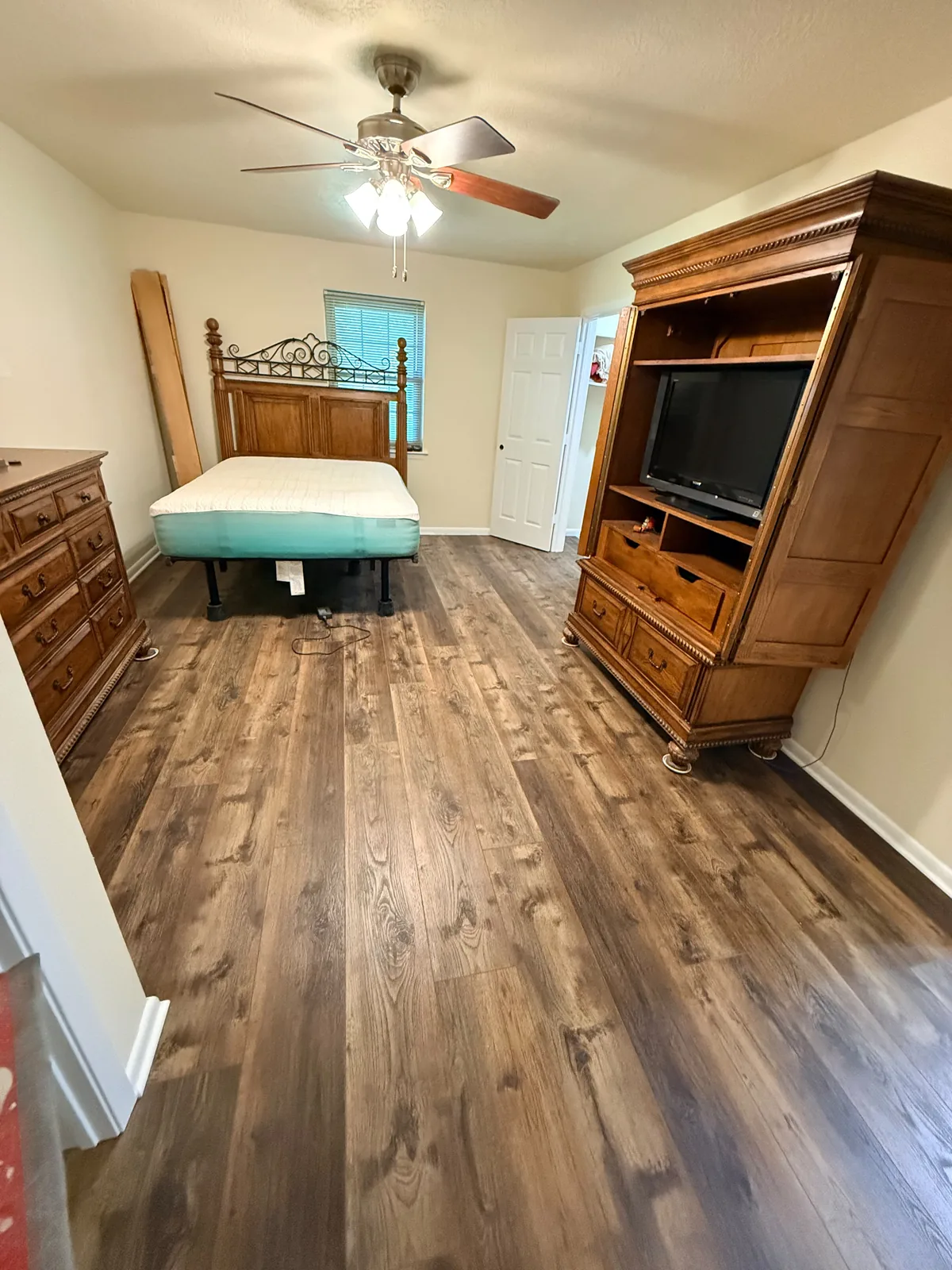Master bedroom after new plank flooring ran wall to wall, with baseboard reset and the room put back together.